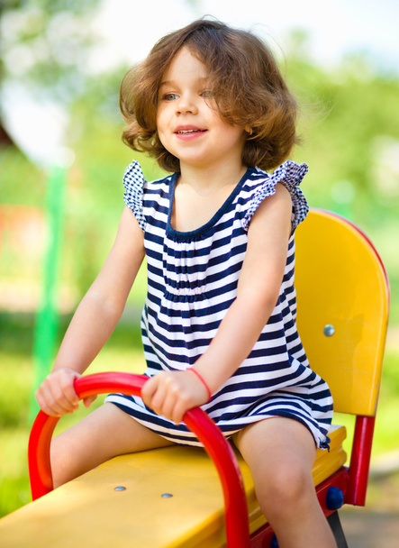 Young happy girl is swinging in playground - Φωτογραφία, εικόνα