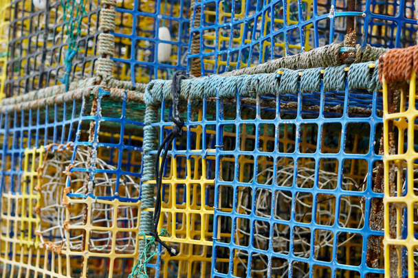 Fischernetze, Hummertöpfe, Ketten und Schwimmer sind rund um die Trawler am Strand von East Hill, Hastings, verstreut. Die Boote sind auf See auf der Suche nach dem Fang des Tages.  - Foto, Bild