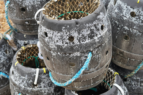 Fishing nets, lobster pots, chains and floats are strewn around the working trawlers at the beach at East Hill, Hastings. The boats are at sea searching for the catch of the day.  - Photo, Image