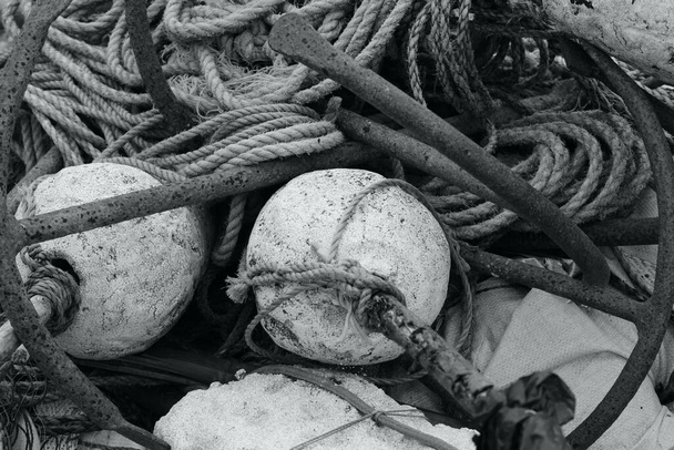 Fischernetze, Hummertöpfe, Ketten und Schwimmer sind rund um die Trawler am Strand von East Hill, Hastings, verstreut. Die Boote sind auf See auf der Suche nach dem Fang des Tages.  - Foto, Bild