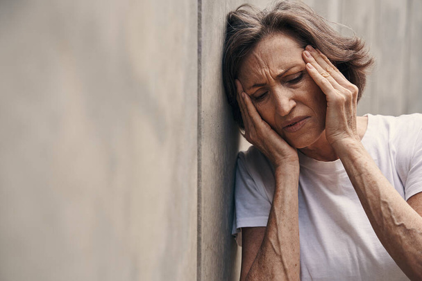 Időskorú nő, aki fejfájástól szenved a szabadban - Fotó, kép