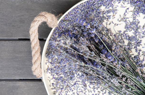 trockener Lavendel auf einem beigen Tablett auf einer hölzernen Tischplatte - Foto, Bild