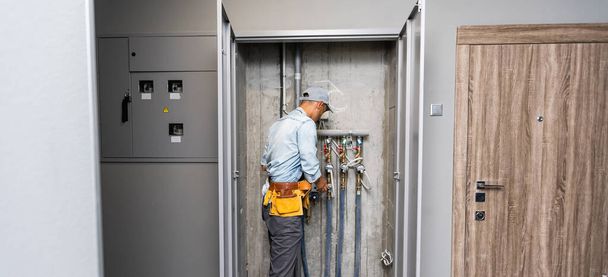 Férfi vízvezeték-szerelő ellenőrzi csövek központi meleg és hideg vízellátás lakás - Fotó, kép