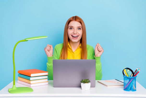 Photo of hooray red hairdo young lady hands fists work laptop wear green cardigan work from home isolated on blue background - 写真・画像