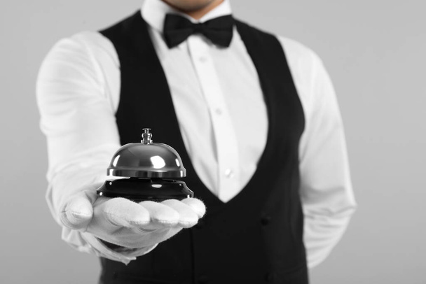 Butler holding service bell on grey background, closeup - Foto, Imagem