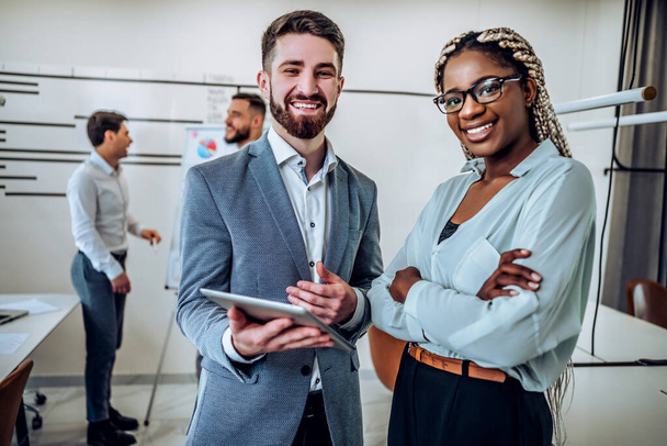 Two young business people are standing together in the office and are talking to each other. Business concept - Photo, Image