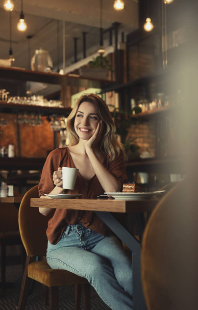 Young woman with cup of coffee at cafe in morning - Foto, Imagem