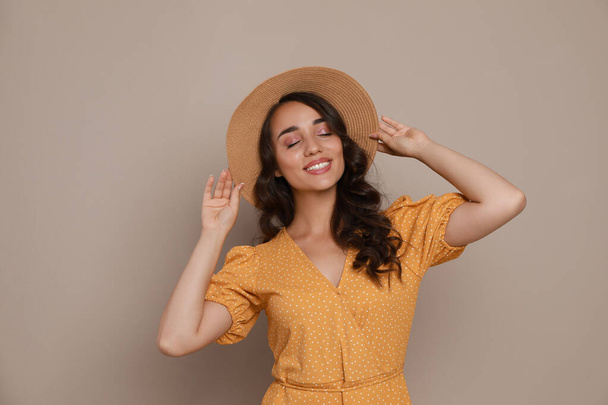 Beautiful young woman with straw hat on beige background - Foto, afbeelding