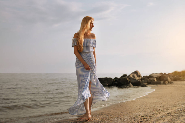 Beautiful young woman near water on sea beach - Photo, image