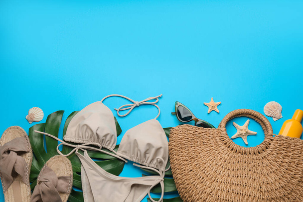 Κομψή τσάντα με αξεσουάρ παραλίας σε γαλάζιο φόντο, επίπεδη lay. Χώρος για κείμενο - Φωτογραφία, εικόνα