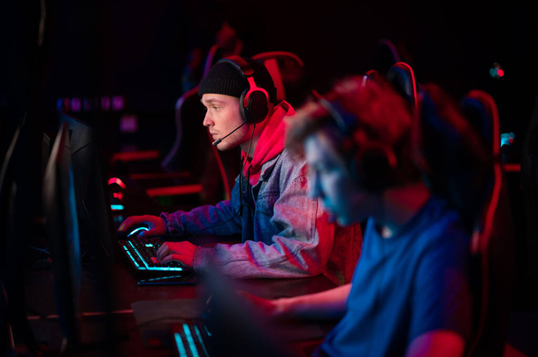 International gaming event. Arena for conducting esports competitions. Young players with headphones are playing a popular online game. - Foto, Bild