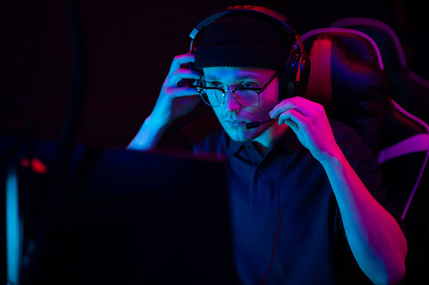 Close-up of the face of a professional video game player at an esports tournament. A cyberathlete wearing headphones and a headset. - Foto, afbeelding