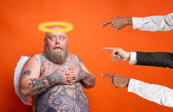 Fat afraid man with beard ,tattoos and wings acts like an angel - Photo, Image