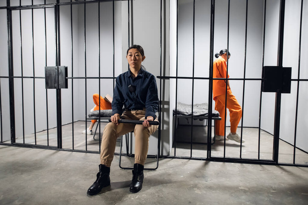 Un día típico en una prisión de mujeres. Una guardia aburrida en uniforme se sienta cerca de las celdas con presas. - Foto, Imagen