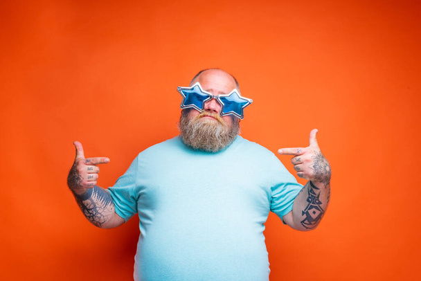Fat doubter man with beard, tattoos and sunglasses is uncertain for something - Foto, imagen