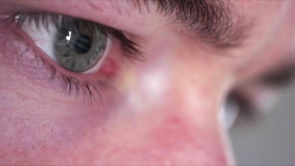 Refleksja ekranu na niebieskim zielonym oku osoby w ciemnym pomieszczeniu - Materiał filmowy, wideo