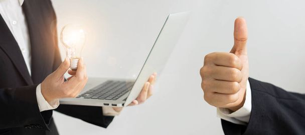 Uomo d'affari con lampadina e laptop, concetto di risparmio energetico, sfondo bianco - Foto, immagini