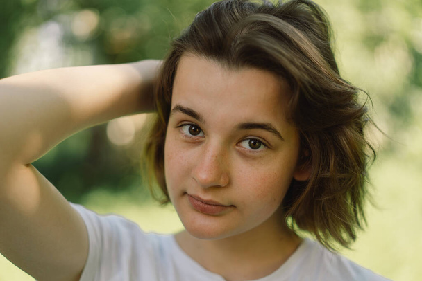 Krásná mladá teenager dívka s trendy bob vlasy v bílém tričku v venkovní a dívá se na kameru. - Fotografie, Obrázek