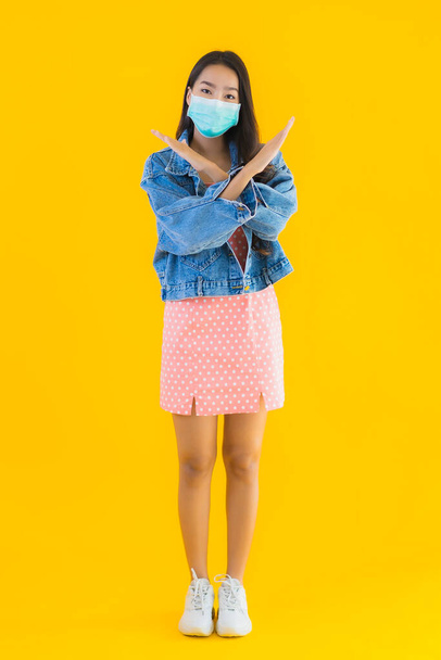 Portrait beautiful young asian woman wear mask for protect coronavirus or covid19 on yellow isolated background - Φωτογραφία, εικόνα