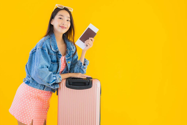 Portret mooie jonge Aziatische vrouw met bagage reistas met paspoort en instapkaart ticket op gele geïsoleerde achtergrond - Foto, afbeelding