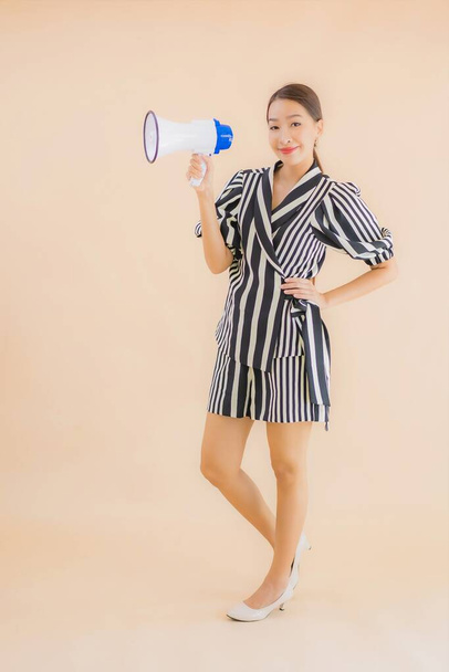 Portret pięknej młodej azjatyckiej kobiety z megafonem na brązowym tle - Zdjęcie, obraz