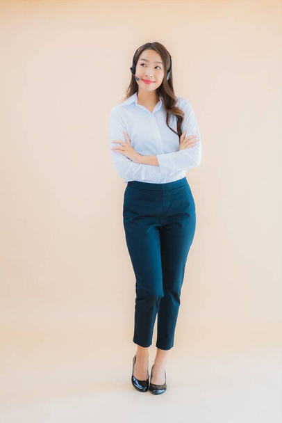 Ritratto bella giovane donna d'affari asiatica con cuffia per call center sul colore sfondo isolato - Foto, immagini
