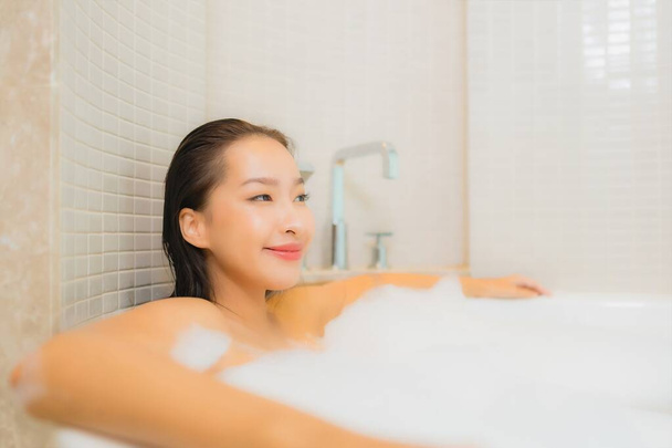 Портрет красива молода азіатка розслабляє посмішку у ванній кімнаті в інтер'єрі ванної
 - Фото, зображення
