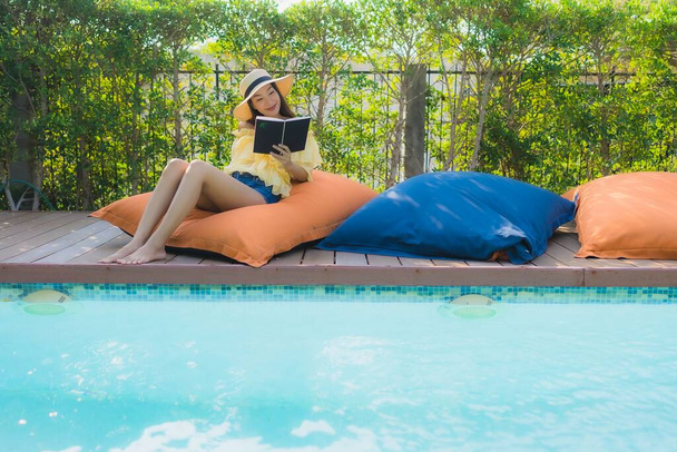 Portrait jeune femme asiatique lire livre autour de la piscine extérieure dans la station hôtelière - Photo, image