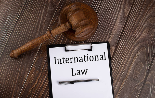 Διεθνές Δίκαιο κείμενο σε χαρτί με σφυρί σε ξύλινο φόντο - Φωτογραφία, εικόνα