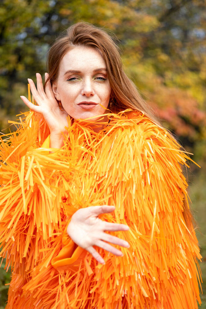 Emotional girl in bright clothes posing in the autumn garden - Valokuva, kuva