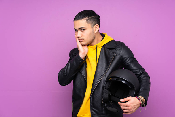 Man with a motorcycle helmet isolated on purple background unhappy and frustrated - Photo, image