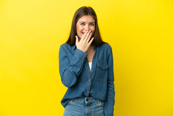 Young caucasian woman isolated on yellow background happy and smiling covering mouth with hand - Zdjęcie, obraz