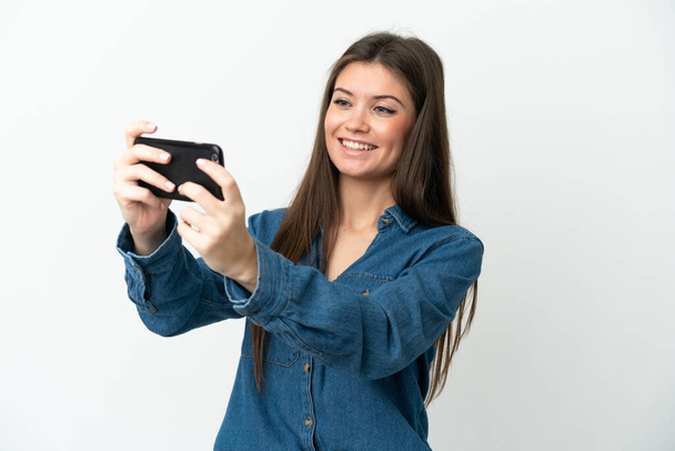 Giovane donna caucasica isolata su sfondo bianco che gioca con il telefono cellulare - Foto, immagini