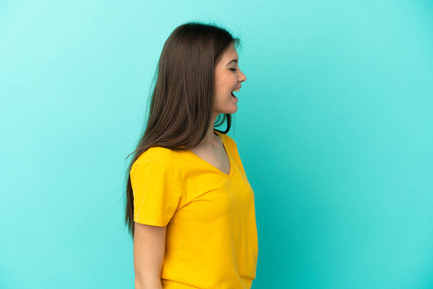 Nuori valkoihoinen nainen sinisellä taustalla nauraa sivusuunnassa - Valokuva, kuva