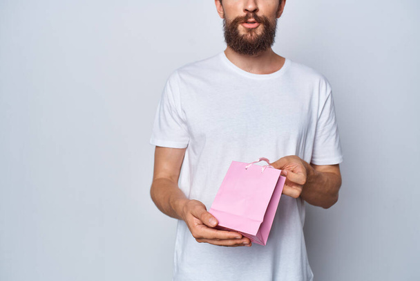 a man in a white t-shirt holding a pink package - 写真・画像