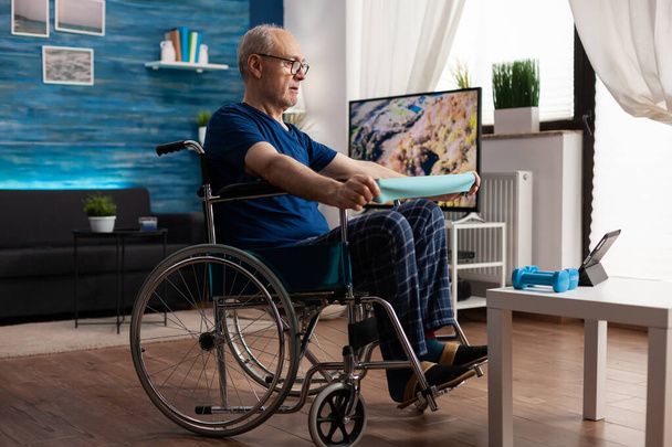 Mozgássérült öregember tolószékben gyakorló kar ellenállás gyakorló test izom - Fotó, kép