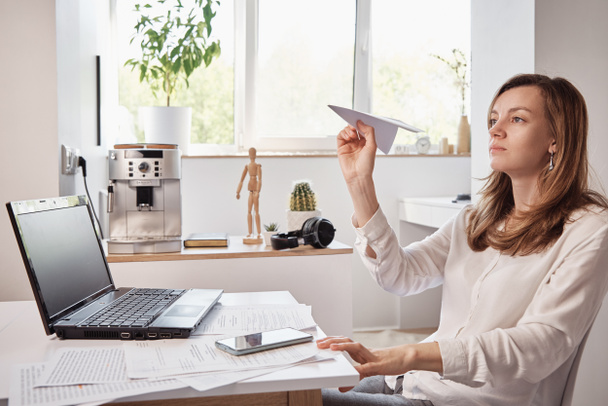 Mulher joga com papel liso em casa escritório. Procrastinar no trabalho remoto - Foto, Imagem