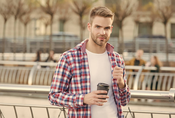 businessman walking outdoor. smart casual dressed person drinking coffee mug outdoor. Caucasian male resting in street on the way to work. Young man in checkered shirt. Enjoying beautiful morning - Foto, imagen