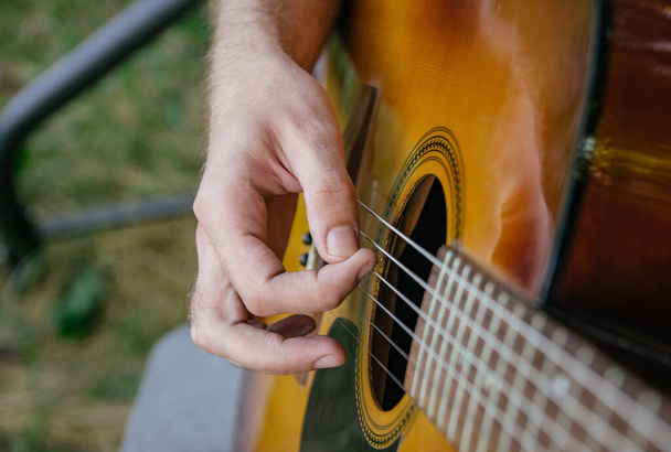 close-up of a guitar playing with a man's hand playing the strings - Fotografie, Obrázek