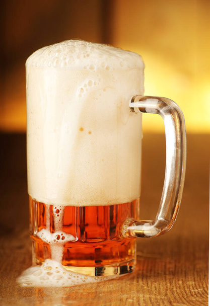 mug full of beer with foam on the background of wooden boards - Photo, Image