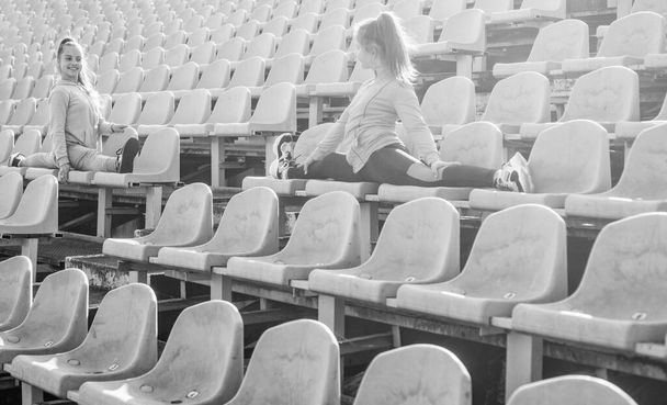Leg stretches. Teenage girls do splits on stadium seats. Stretching exercises. Stretching routine - Φωτογραφία, εικόνα