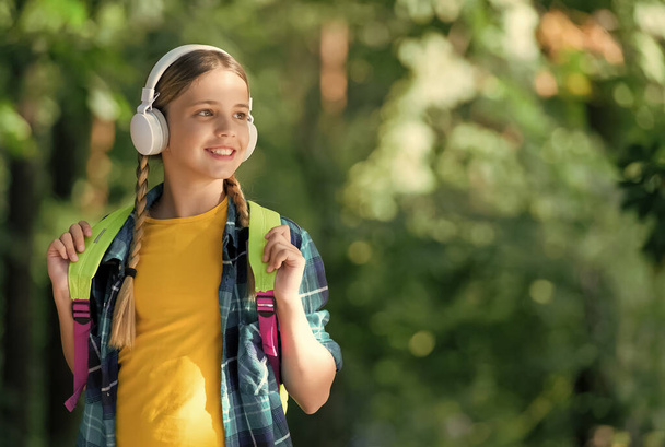Bringing joy through sound. Little kid listen to music natural outdoors. Hi-Fi stereo sound. New technology. Modern life. Summer vacation. Travel and wanderlust. Add memories with sound, copy space - Photo, image