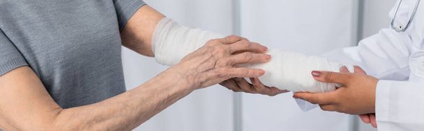 Afro-Amerikalı doktorun alçı bandaj ve pankartıyla hastanın koluna dokunuşu.  - Fotoğraf, Görsel