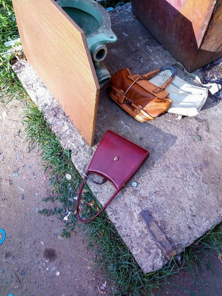 A red leather purse is lying on the ground, thrown into the trash. - Φωτογραφία, εικόνα