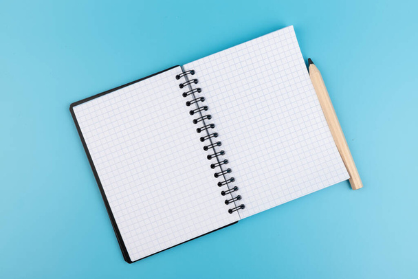 lápices y cuaderno en blanco sobre fondo azul con espacio para copiar - Foto, imagen