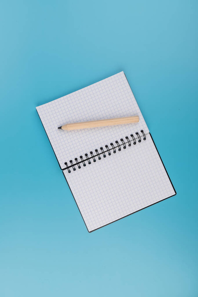 crayons et bloc-notes vierges sur fond bleu avec espace de copie - Photo, image
