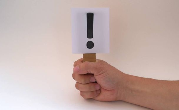 A white sign with an exclamation mark in his hand on a white background - Foto, Bild