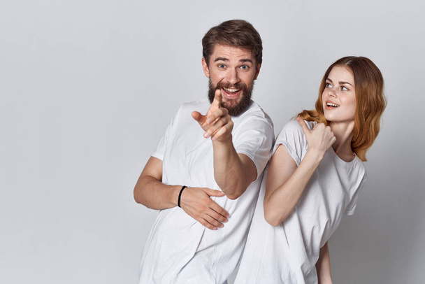 χαρούμενο νεαρό ζευγάρι σε λευκό t-shirts ποζάρουν φως της μόδας φόντο - Φωτογραφία, εικόνα