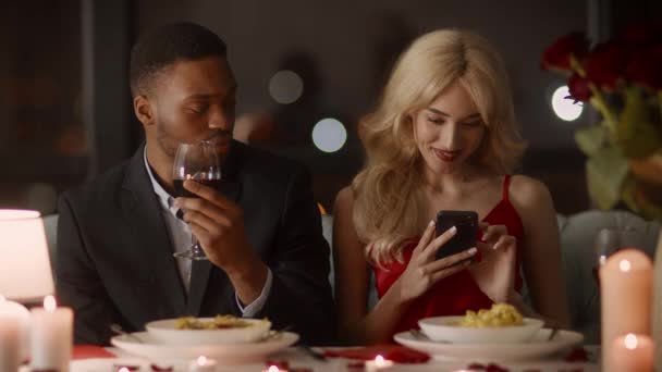 Zazdrosny chłopak podejrzewa romans, podczas gdy dziewczyna za pomocą telefonu komórkowego w restauracji - Materiał filmowy, wideo