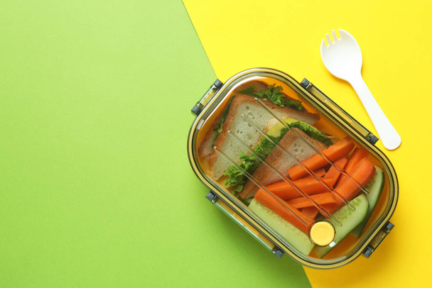 Lunch box with tasty food on two tone background - Foto, Imagen